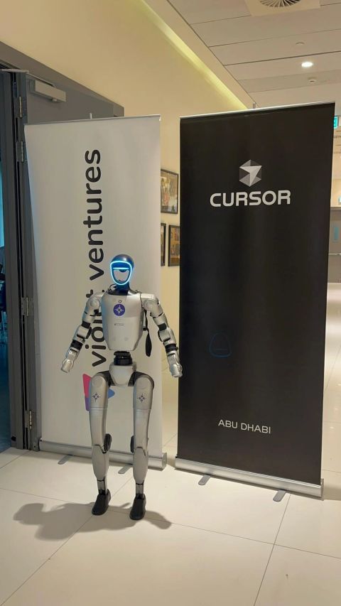 Robot beside Violet Ventures and Cursor Abu Dhabi banners